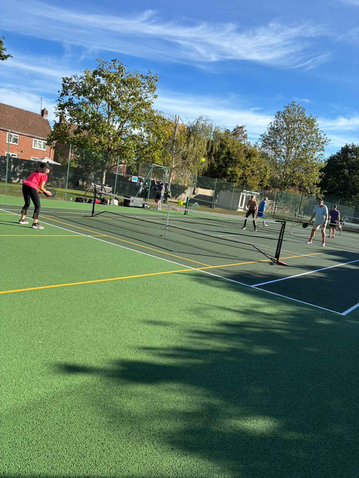 Players rallying during a pickleball clinic on a sunny court